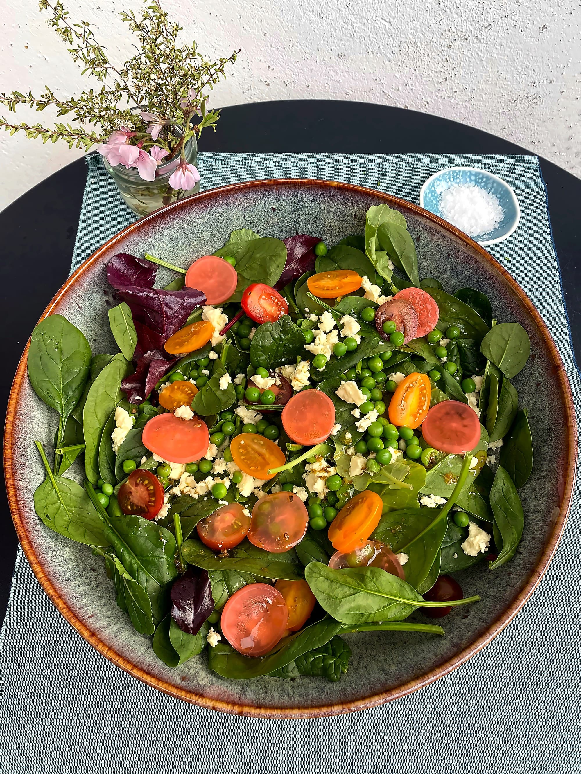 Spring salad with peas, cherry tomatoes, feta, and pickled radishes.